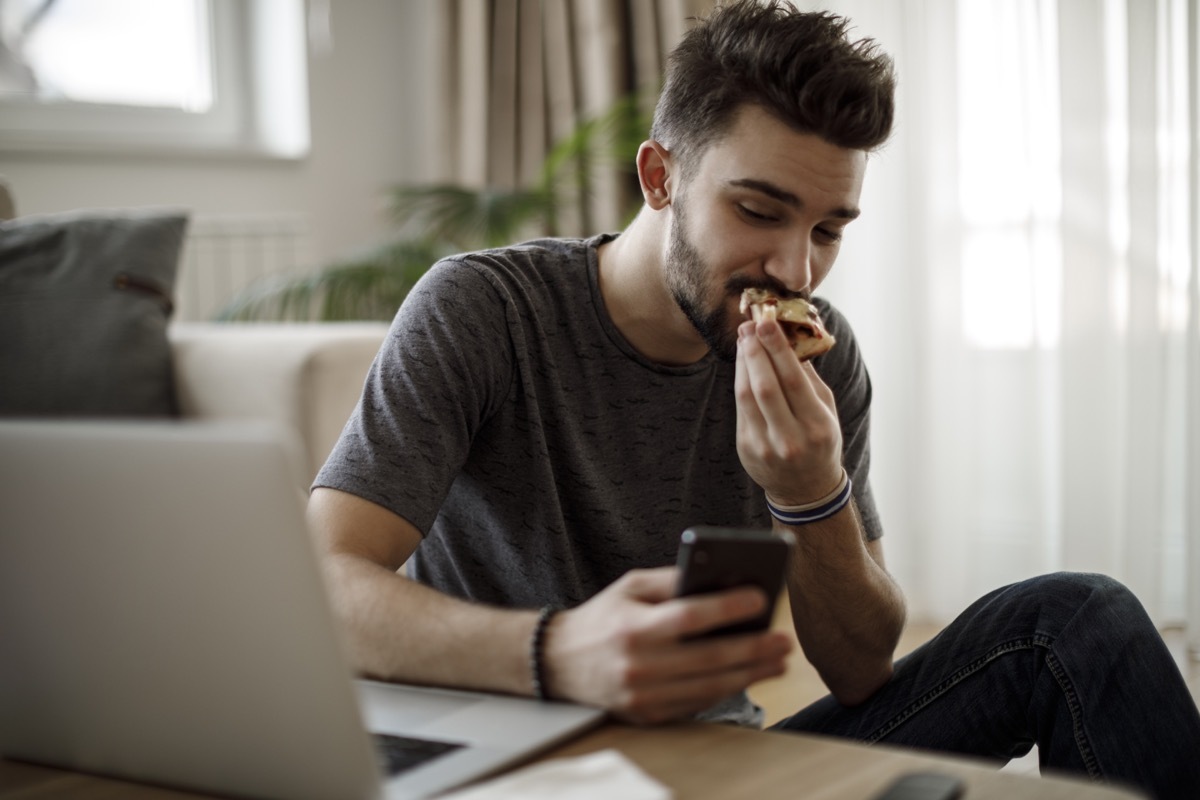 Smiling young man using social media at home