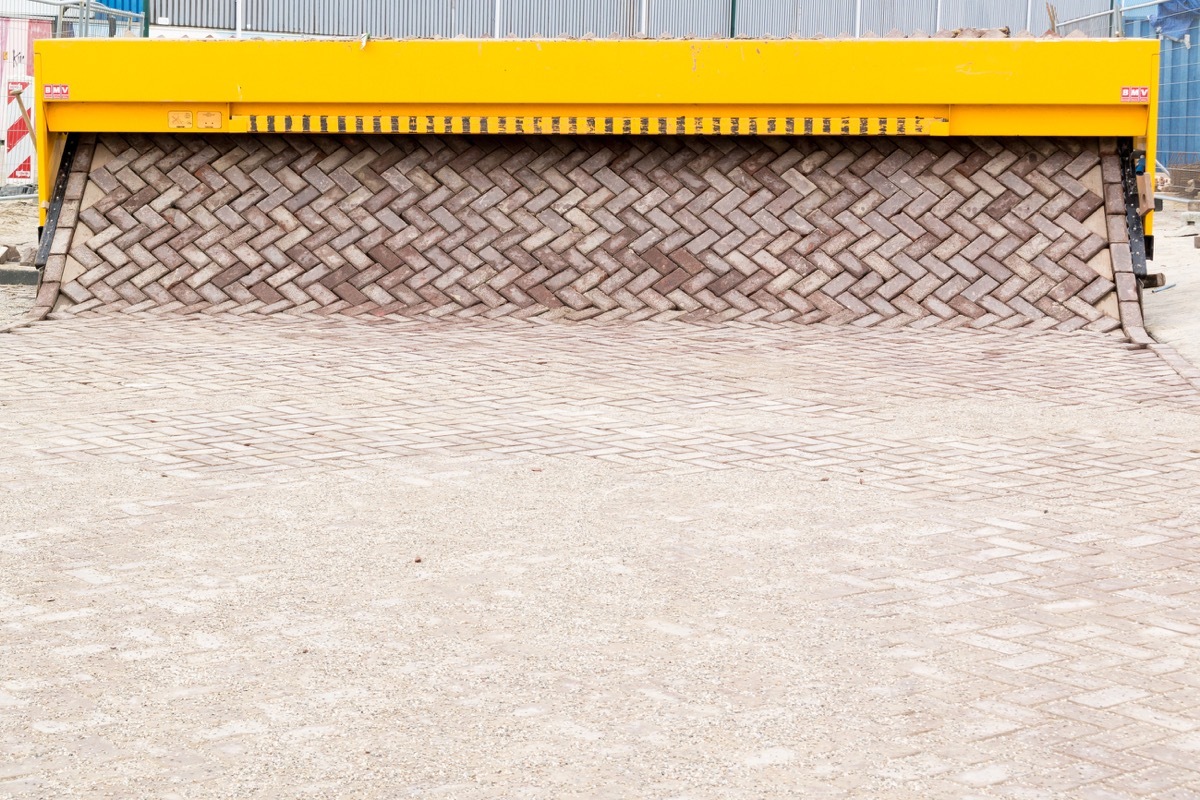 a machine printing out a brick road and laying it down
