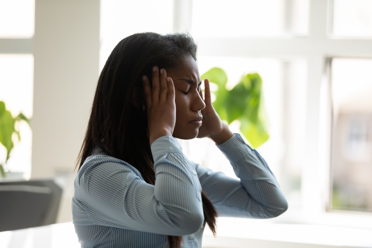 Unhappy african american businesswoman suffering from headache at work at laptop.