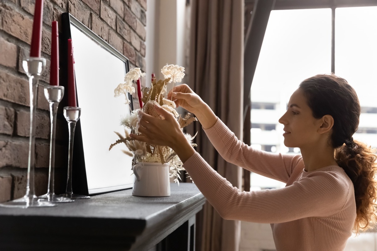 woman putting vase on mantel