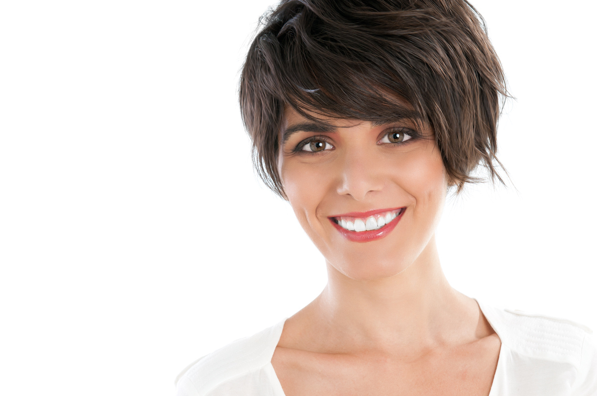 Portrait of a young brunette woman with a shaggy pixie haircut on a white background