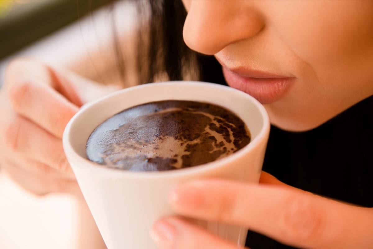 Woman trying to smell a cup of coffee