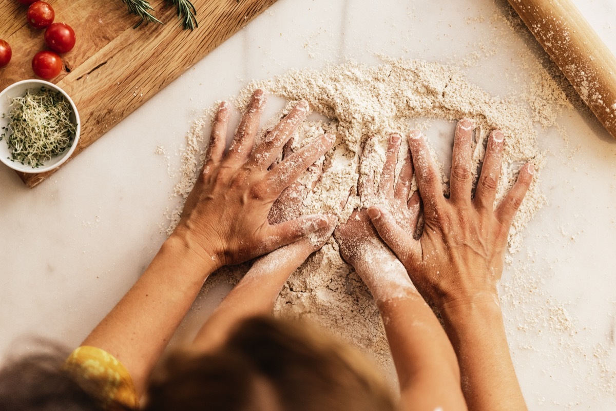 Closeup of mother and child's hands kneading dough