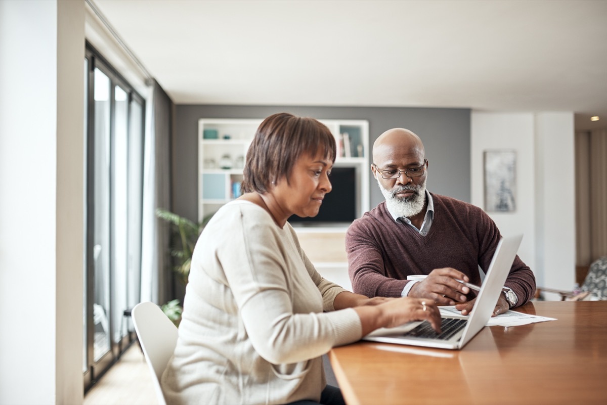 A mature couple looking at a laptop together while sitting at their dining room table