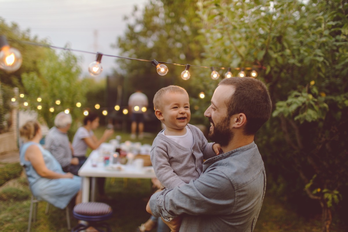 white man holding baby and smiling at outdoor party