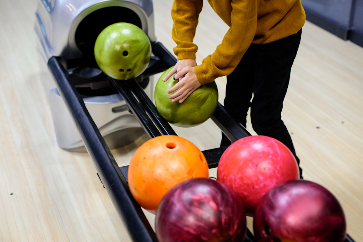 closeup of hands grabbing ball at bowling alley