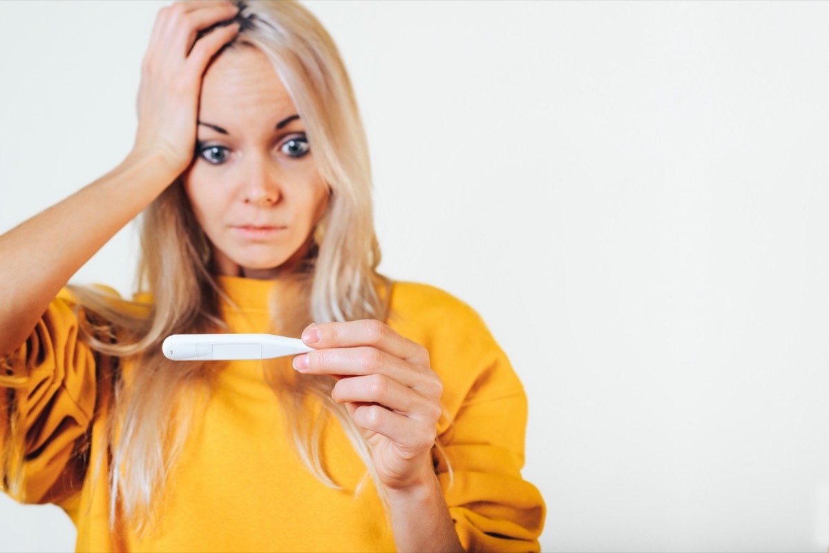 The surprised girl holds a thermometer in her hands.
