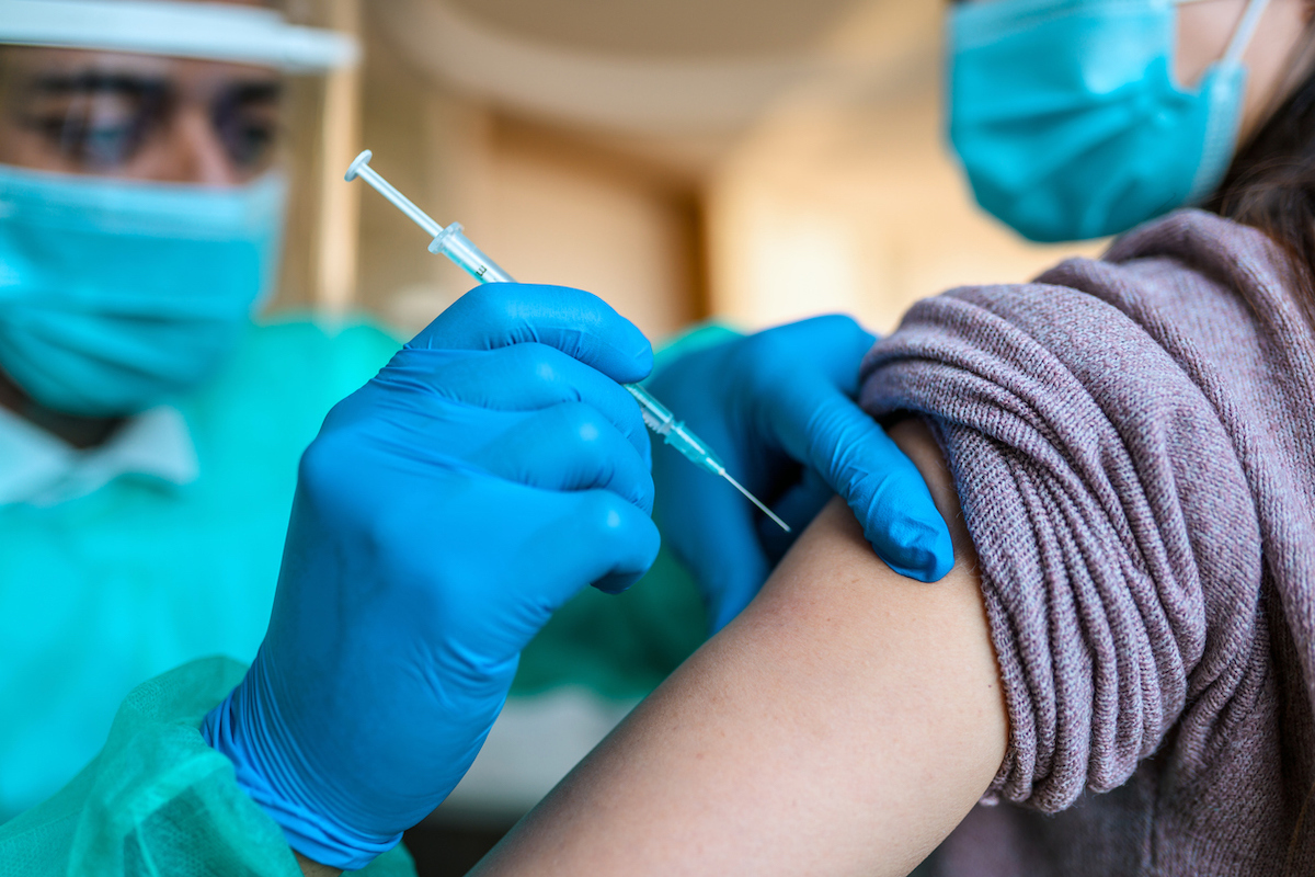 Closeup of doctor sitting in a doctor's office and is vaccinating patient