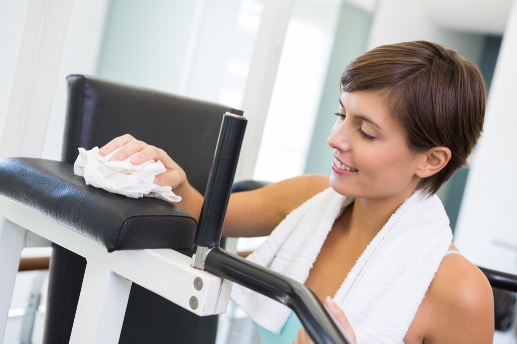 woman cleaning gym equipment