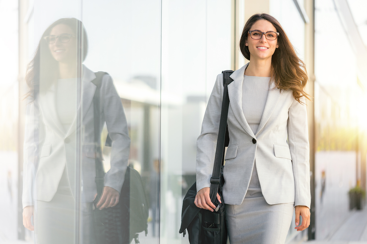 Female businesswoman in beige suit walking next to building