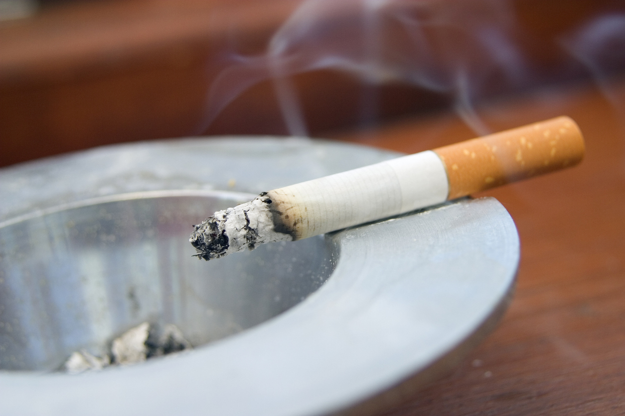 Burning cigarette in ashtray.