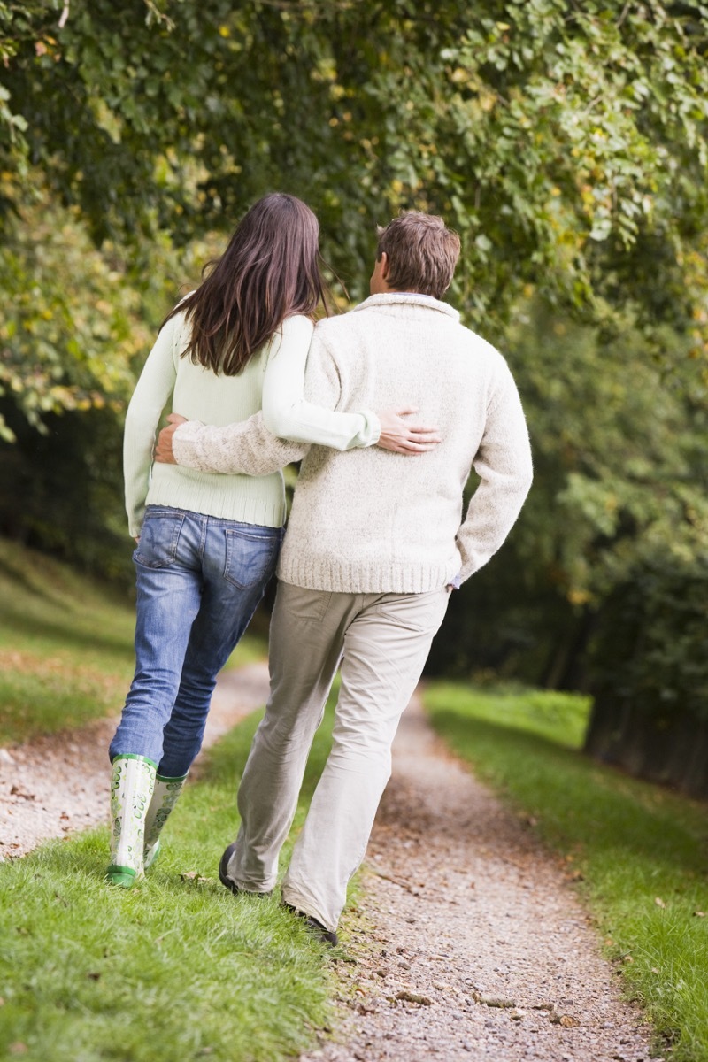 Couple walking in countryside from behind, widow at 40