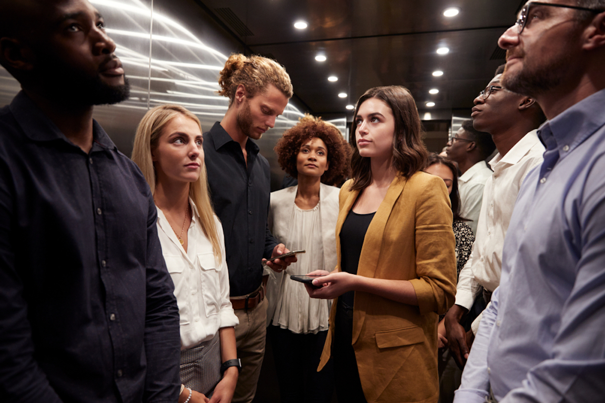  Work colleagues stand waiting together in an elevator at their office