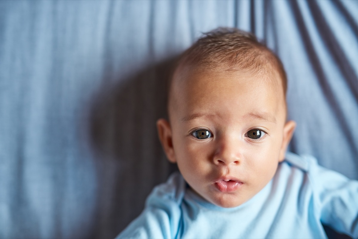 Portrait of an adorable baby boy laying on the bed at home