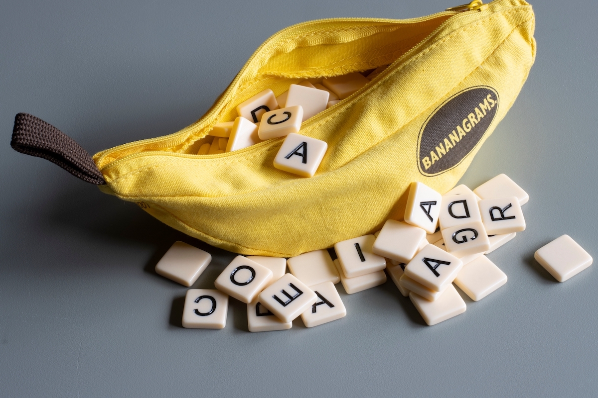 Bananagrams portable banana-shaped pouch with letter tiles isolated on a gray background.