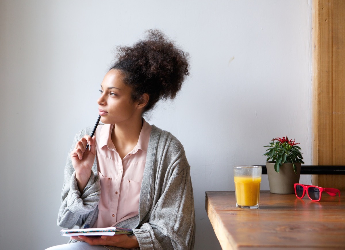 woman looking pensive holding a pen and paper