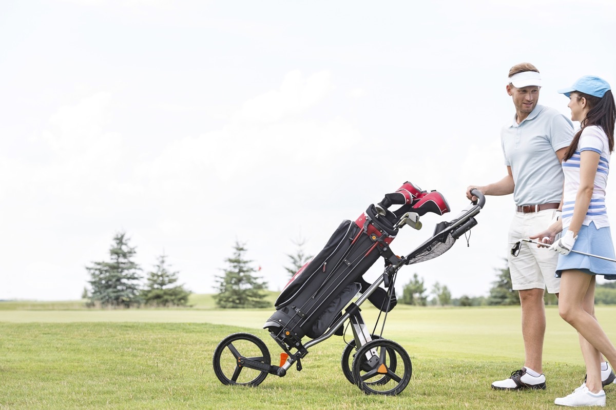 male and female golfers using a pushcart