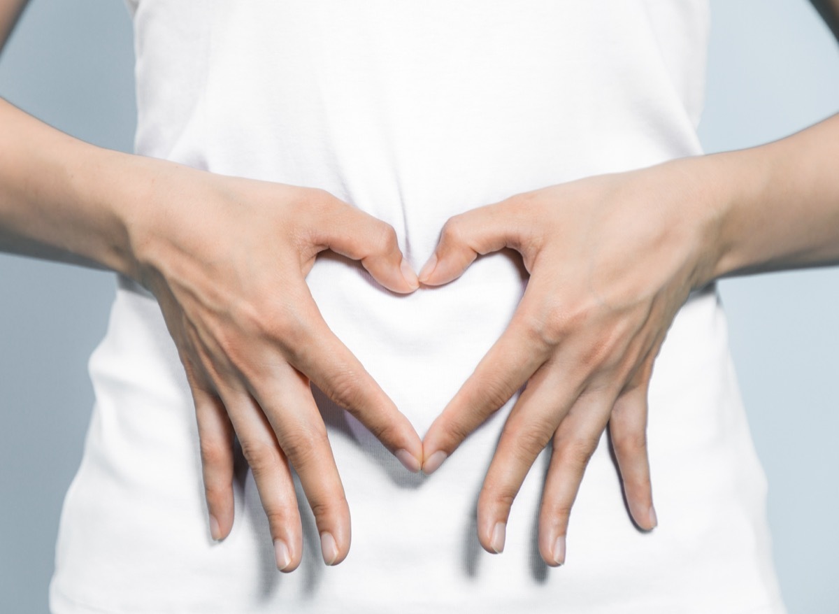 Close up of a woman making a heart with her hands over her staomach