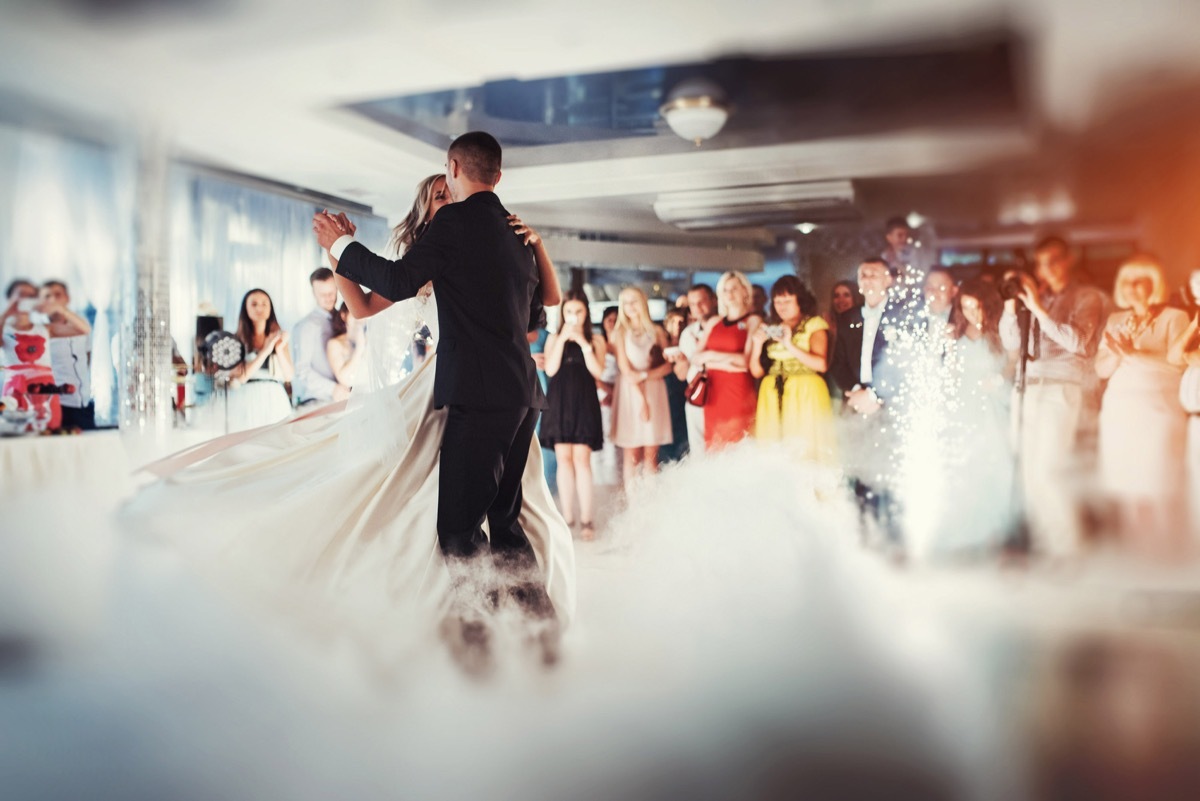 Artistic shot of a bride and groom having their first dance in front of their guests