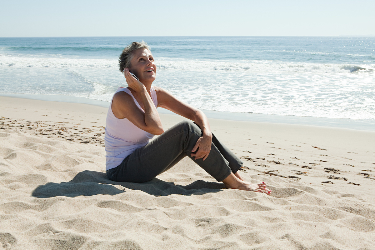 Senior woman on beach on phone