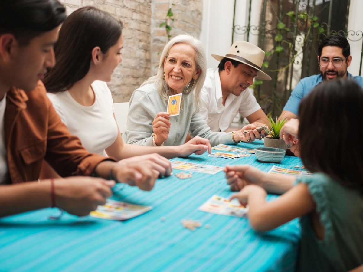 A smiling grandmother sitting with her family playing a card game