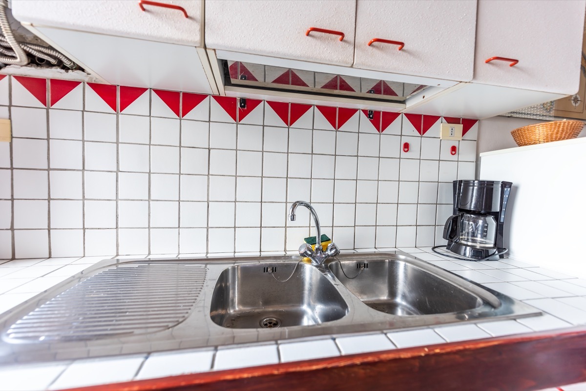 outdated kitchen with old red and white tile counter