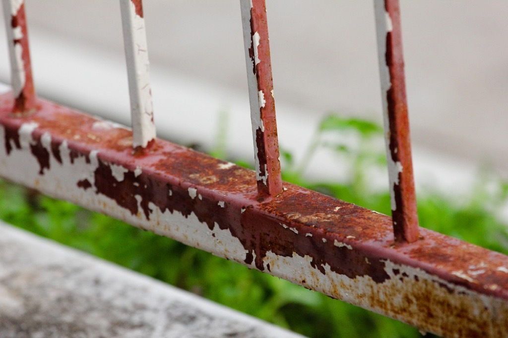 rusty porch railing with chipping white paint