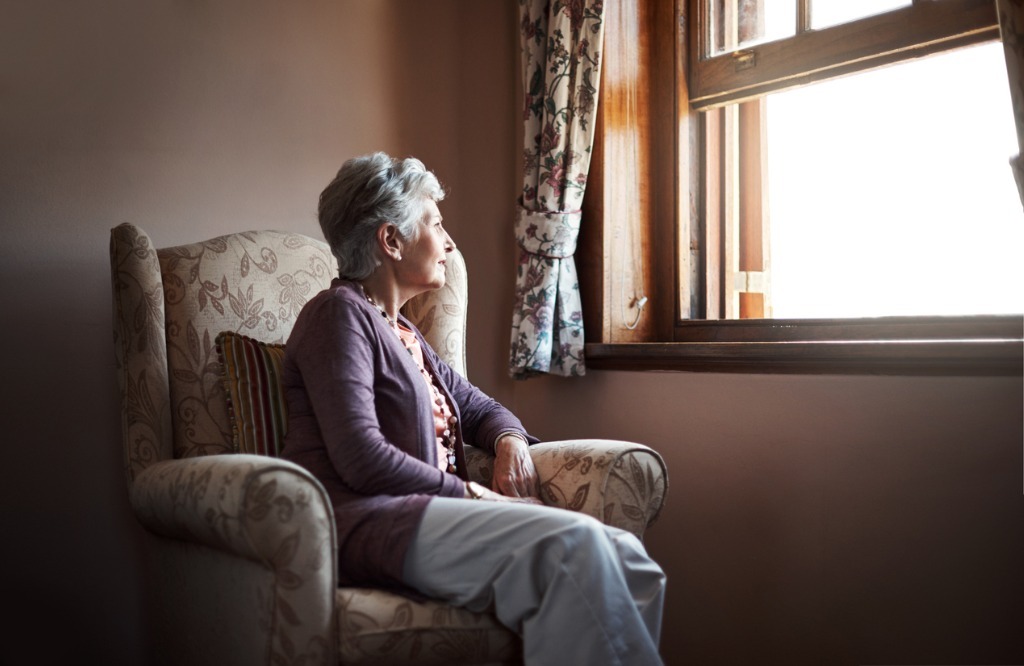 Senior woman sitting on a chair looking out the window.