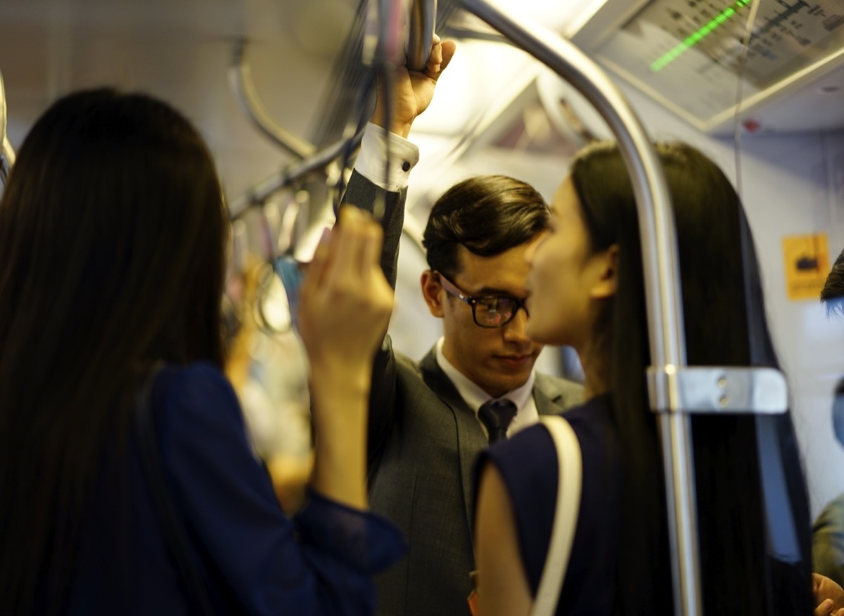 young asian people handing onto public transportation railing