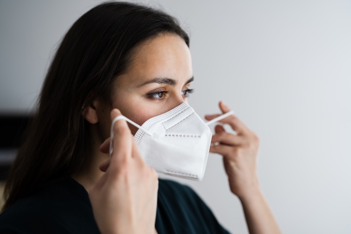 Woman putting on medical N95 face mask.