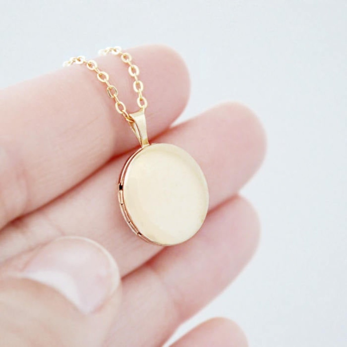 hand holding gold locket, Etsy jewelry