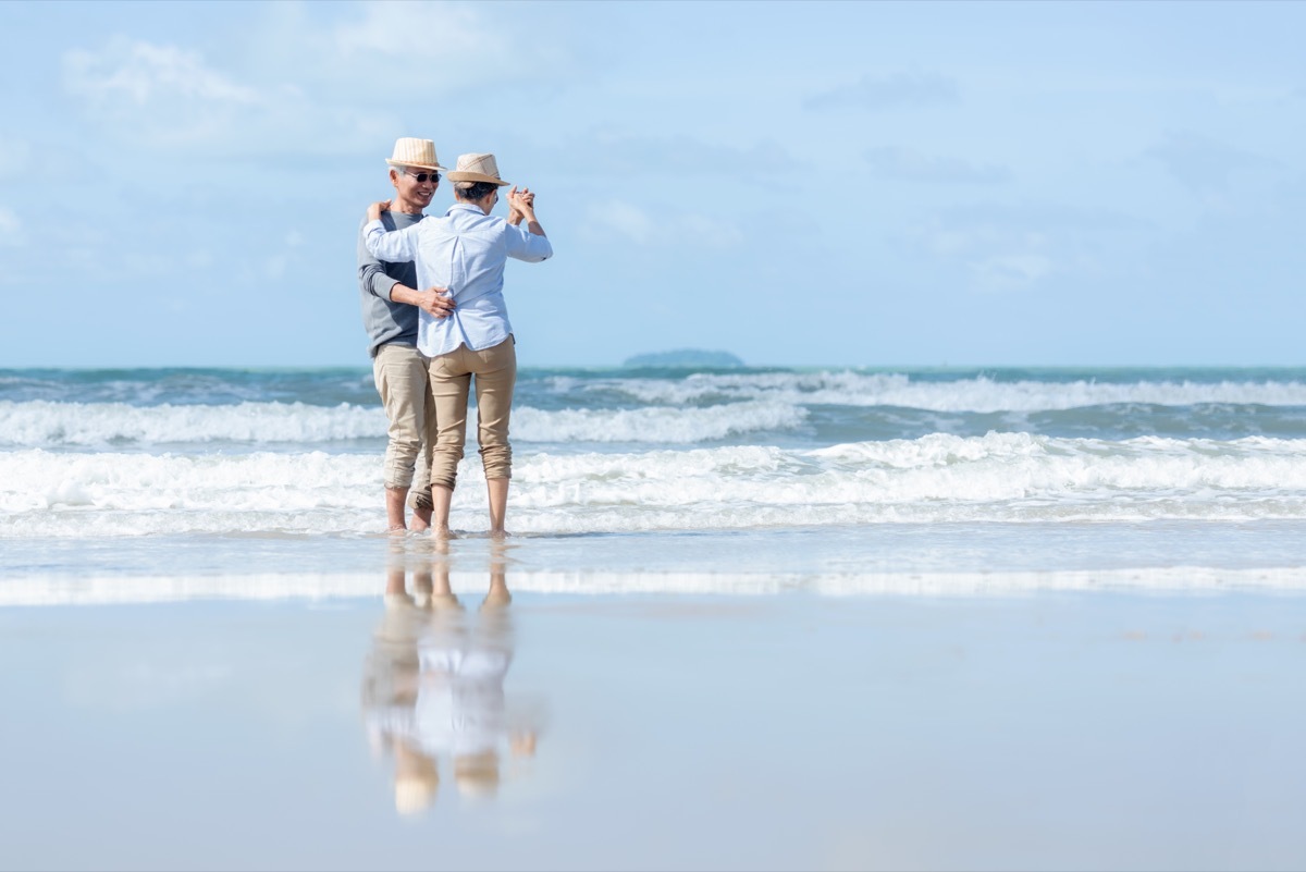 A couple dances on the beach together.