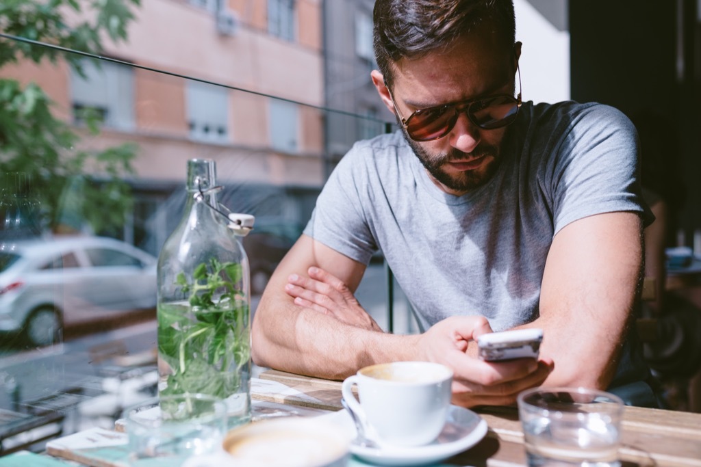 man on his phone at an outdoor cafe, The best opening lines for online dating