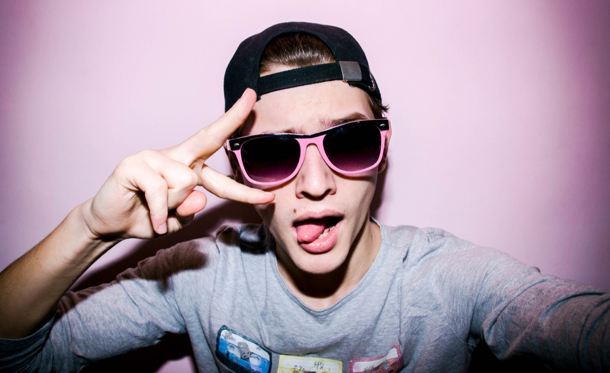 teen boy wearing sunglasses and making a peace sign for an Instagram selfie