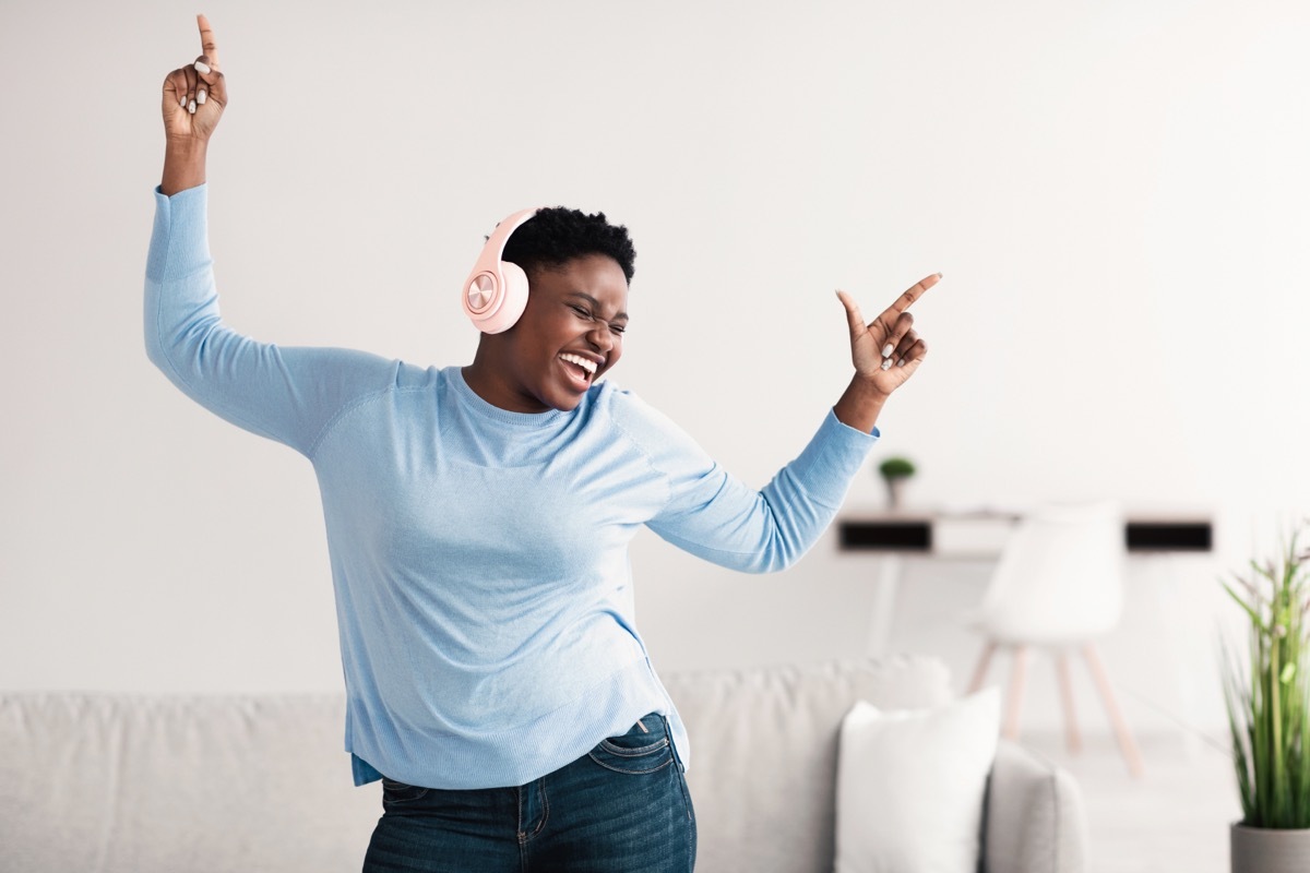 Woman in a blue shirt dancing to music. 