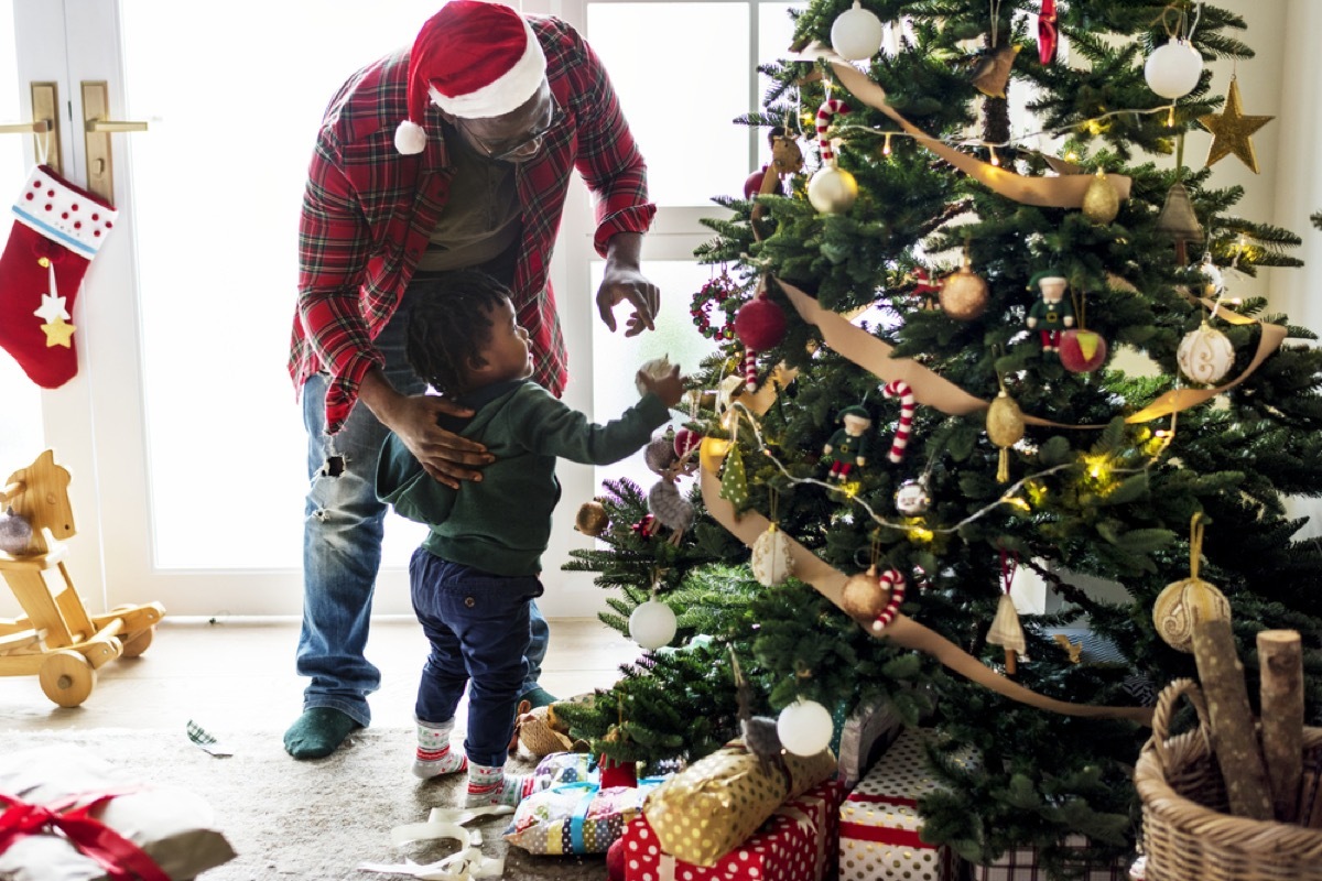 Young father and toddler son decorating Christmas tree