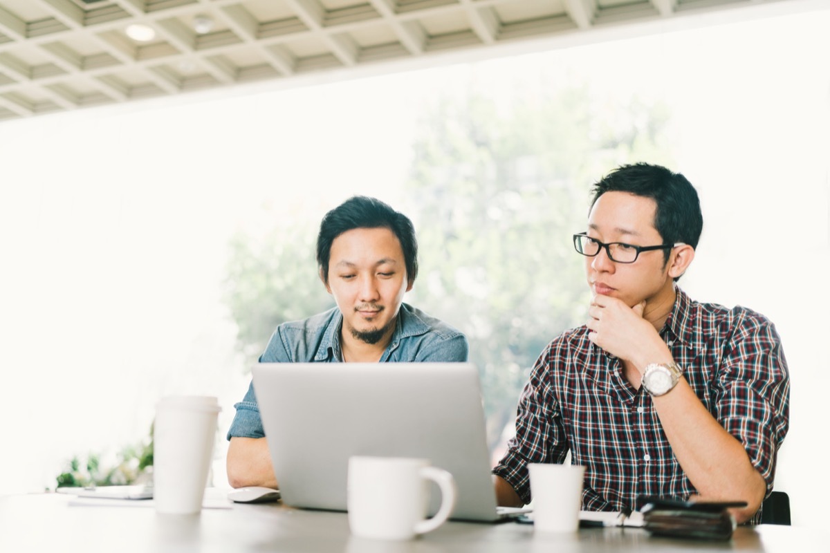 Handsome business colleagues or college students work together using laptop, startup project meeting or teamwork brainstorm concept, at coffee shop or modern office