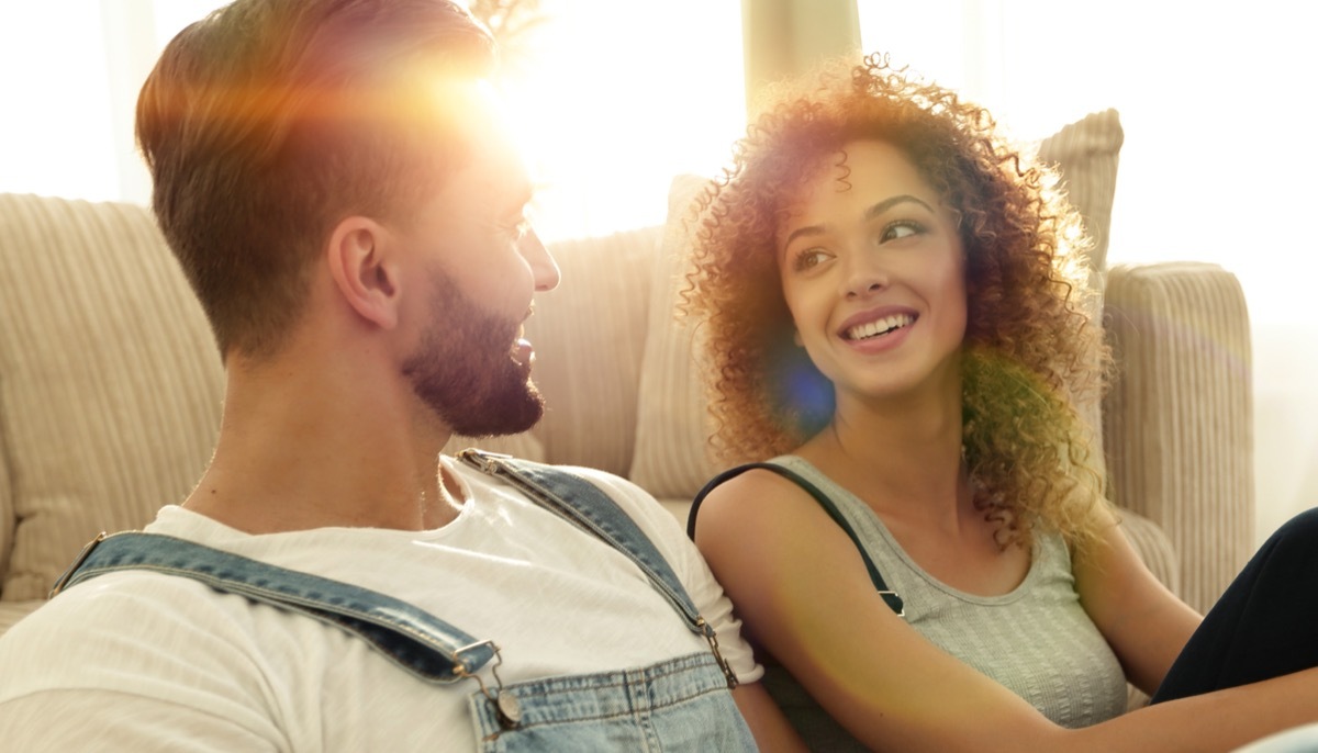 Young couple sitting on floor in front of their couch at sunset