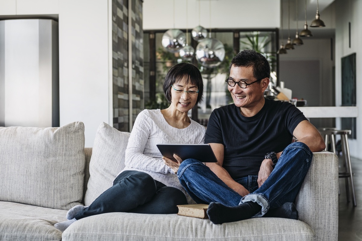man and woman on couch looking at a tablet together