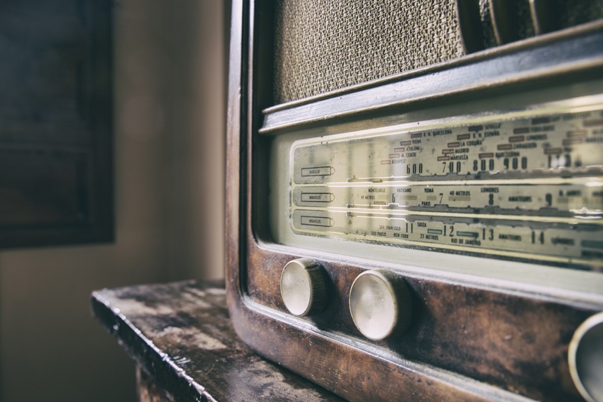 Obsolete radio in wooden case sits on antique table, state fact about kentucky