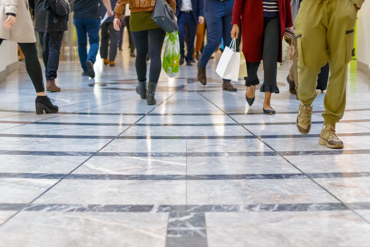 A modern floor with legs of a crowd walking in a shopping mall in the background