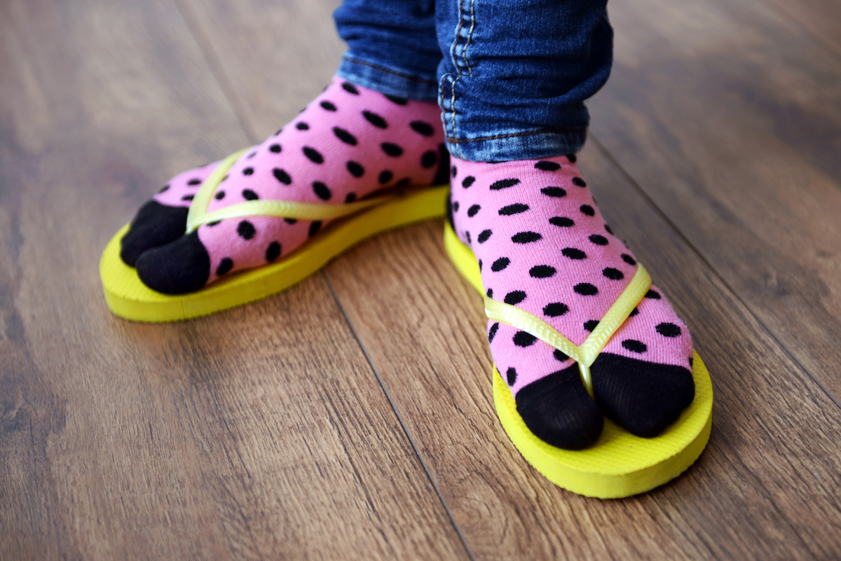 Close up of feet in pink and black polka dot socks with yellow flip flops