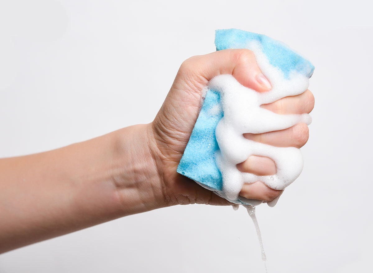 hand squeezing soap from blue sponge
