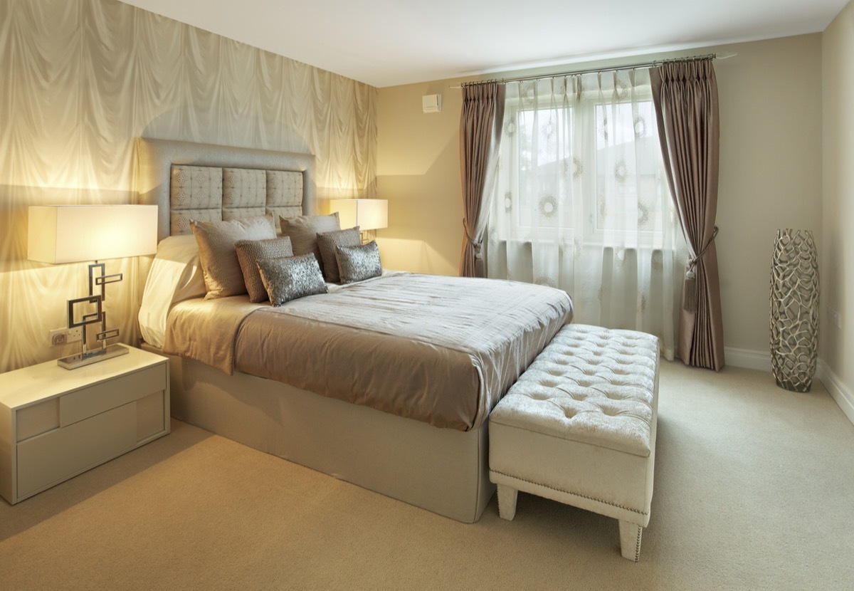 a lovely bedroom in a luxury new apartment with a colour mixture of browns and creams but warmed up by the bedside table lamps which have been turned on for the image. At the end of the bed is a large ottoman stool. Looking for a Bedroom image Then please see my other Bedrooms and related images by clicking on the Lightbox link below