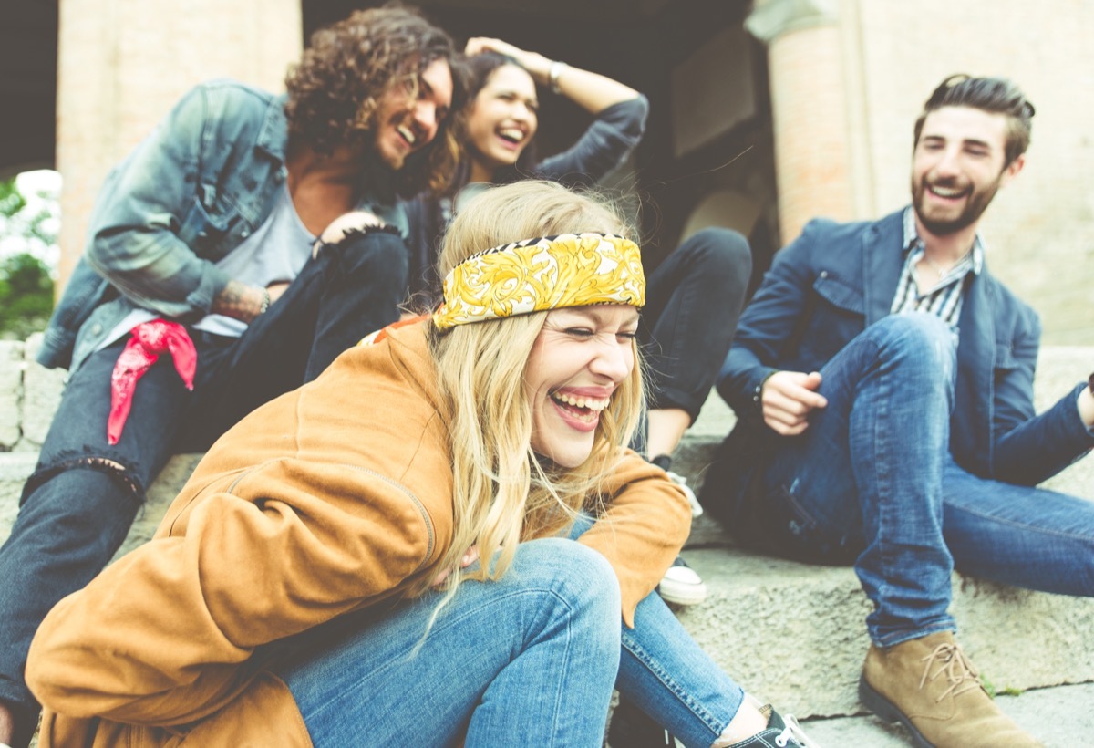 Group of four friends laughing while hanging out outside