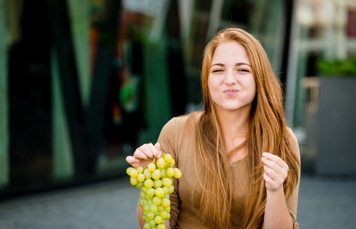 Young woman eating grapes