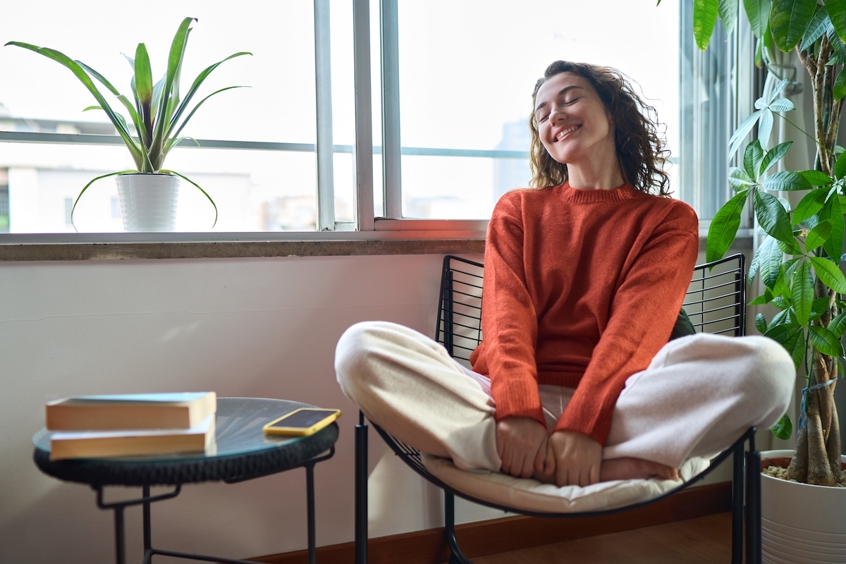 Young relaxed smiling while sitting on a chair at near the window.