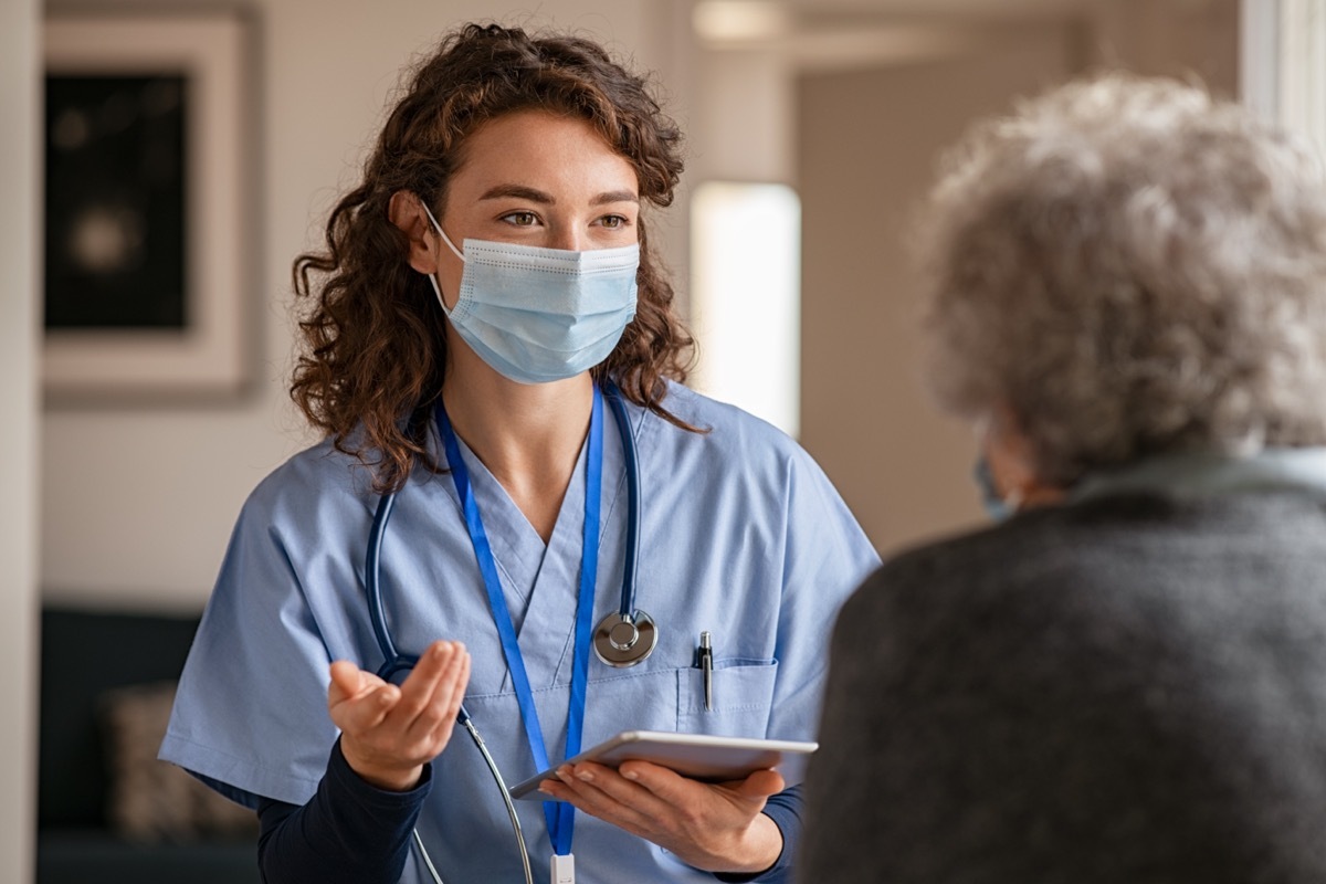 Doctor wearing safety protective mask supporting and cheering up senior patient