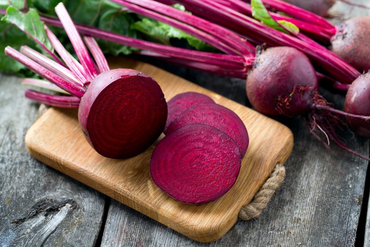 whole and sliced beets on a wooden cutting board