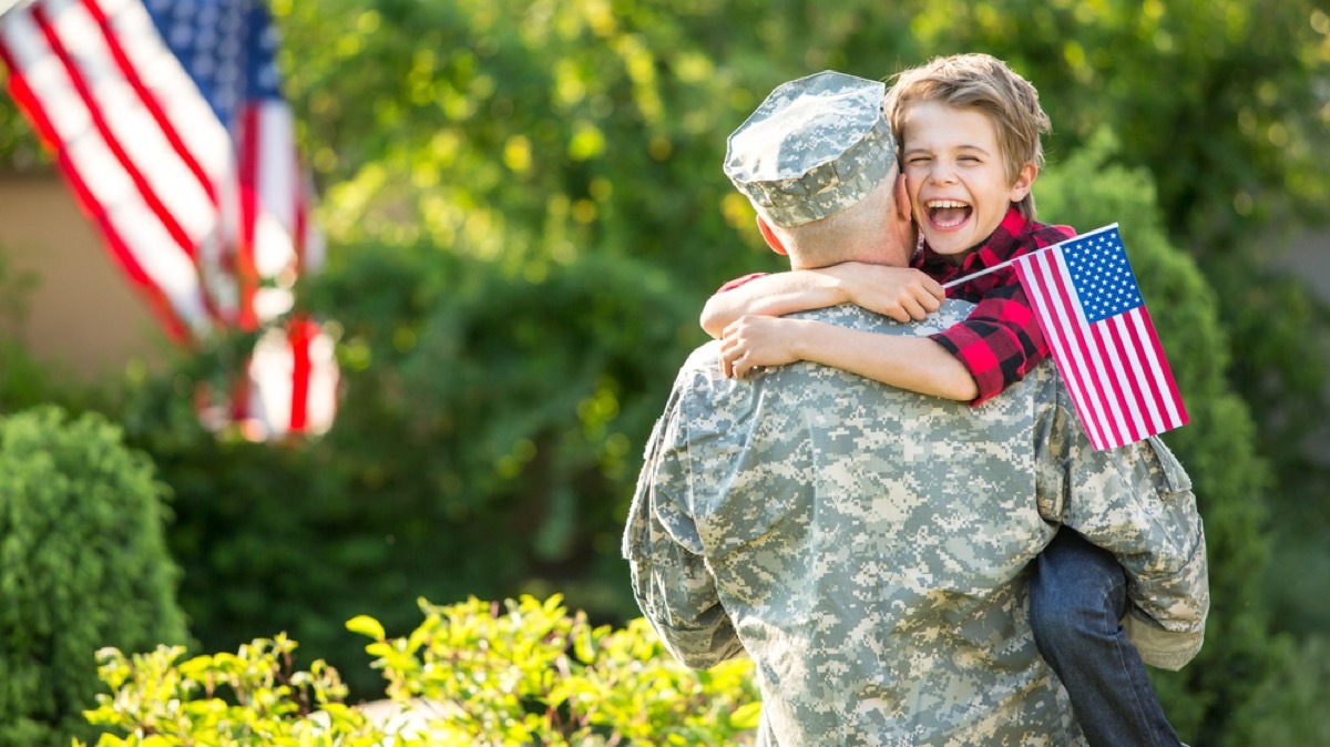 white man in military uniform hugging young son